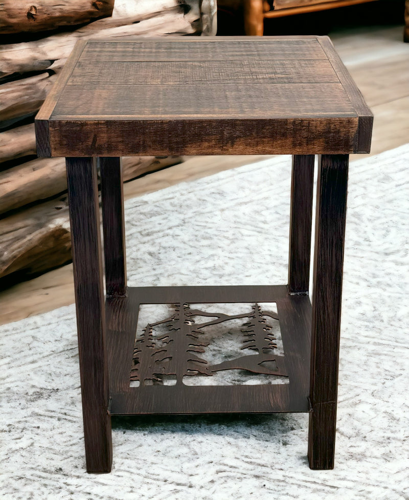Pine  tree design metal leg end table with rough sawn wood top, displayed on wood floor with rustic logs in the background. 