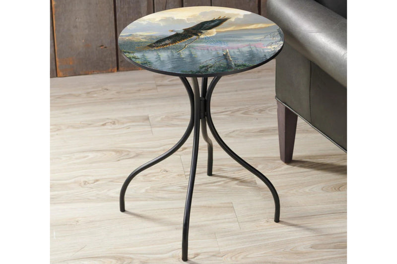 Small round metal side table featuring artwork by Persis Clayton Weirs titled Rebuilding America which features a flying Bald Eagle with the American Flag flying over a forested landscape.
