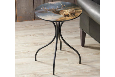 Small round metal side table with a painted top featuring an elk design, placed on a wooden floor.
