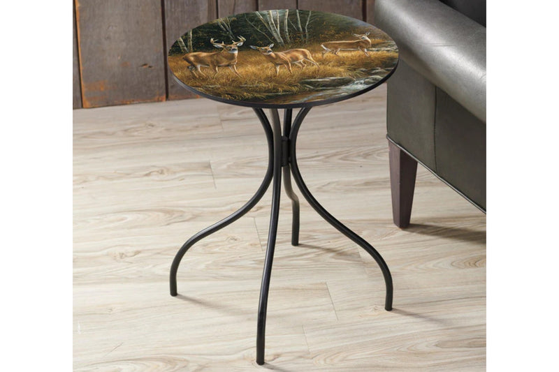 Round metal side table featuring a deer design top sitting on a wood floor.