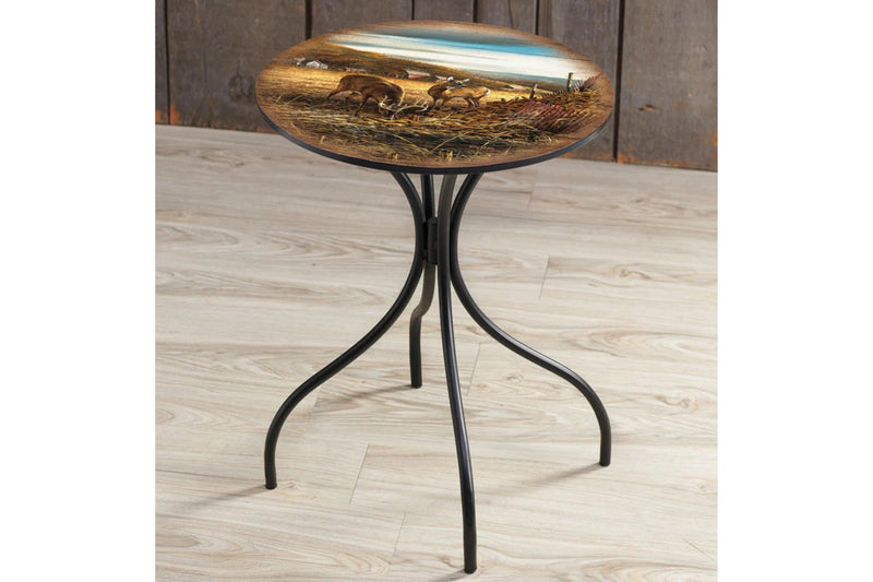Round metal side table with a deer design top sitting on a wood floor.